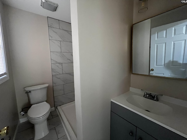 bathroom featuring a tile shower, vanity, and toilet