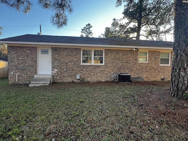 rear view of property with central AC unit and a yard