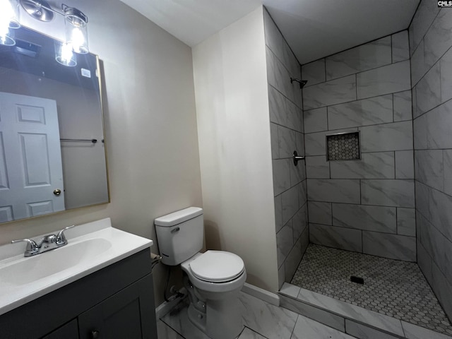 bathroom featuring vanity, toilet, and a tile shower