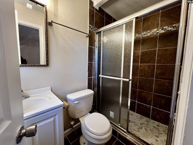 bathroom with an enclosed shower, vanity, toilet, and tile patterned floors