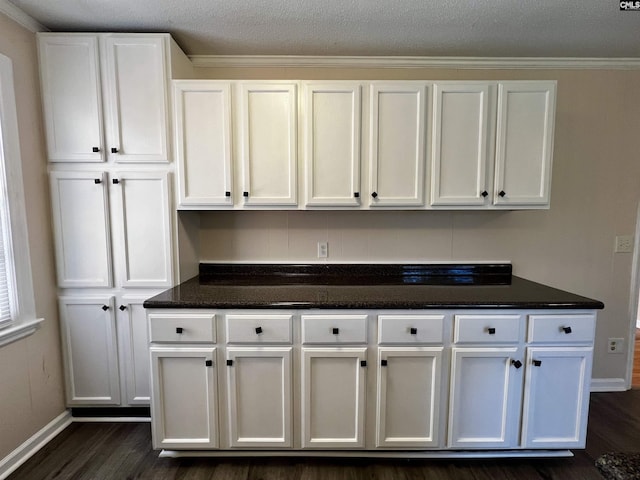 kitchen featuring dark hardwood / wood-style flooring, dark stone countertops, a textured ceiling, white cabinets, and ornamental molding