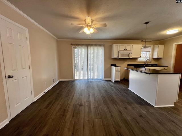 kitchen with dark wood-type flooring, ceiling fan, ornamental molding, decorative light fixtures, and white cabinetry