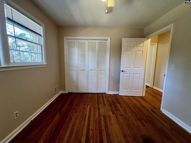 unfurnished bedroom featuring ceiling fan, dark hardwood / wood-style floors, a textured ceiling, and a closet