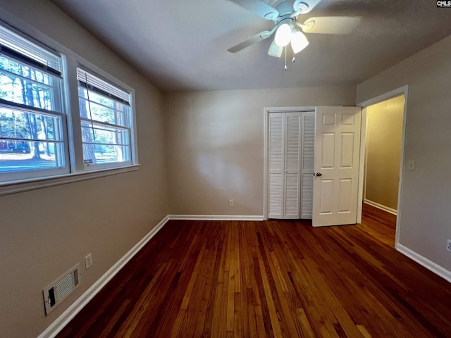 unfurnished bedroom with a closet, ceiling fan, and dark hardwood / wood-style flooring