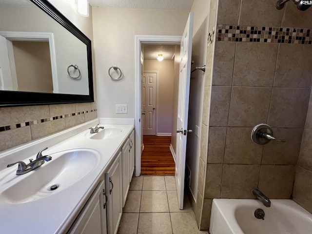 bathroom featuring tile patterned flooring, a textured ceiling, vanity, and tiled shower / bath