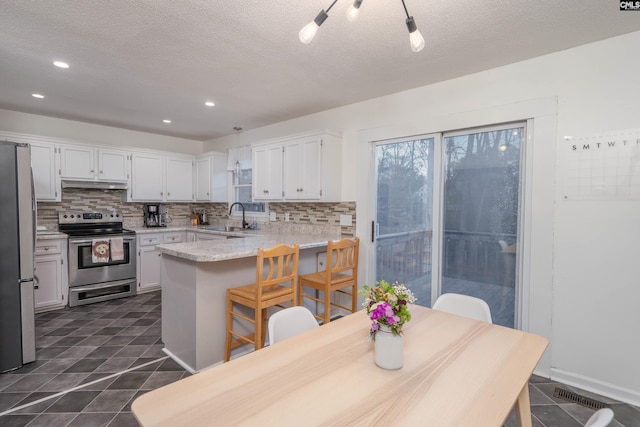 kitchen with backsplash, stainless steel appliances, white cabinetry, and sink