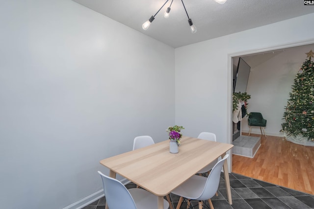 dining area with a textured ceiling and dark wood-type flooring