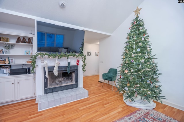 living room with a fireplace, light hardwood / wood-style flooring, and lofted ceiling