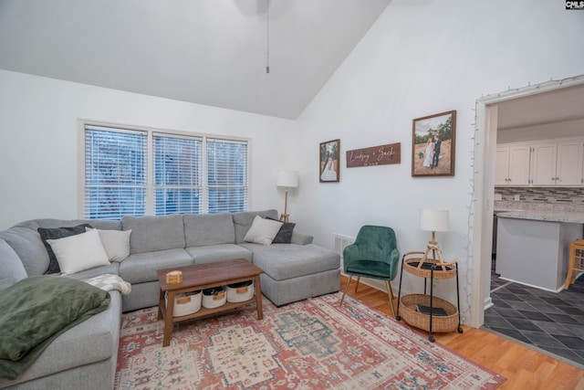 living room with light wood-type flooring and high vaulted ceiling