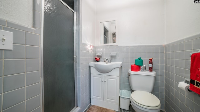 bathroom featuring vanity, toilet, an enclosed shower, and tile walls