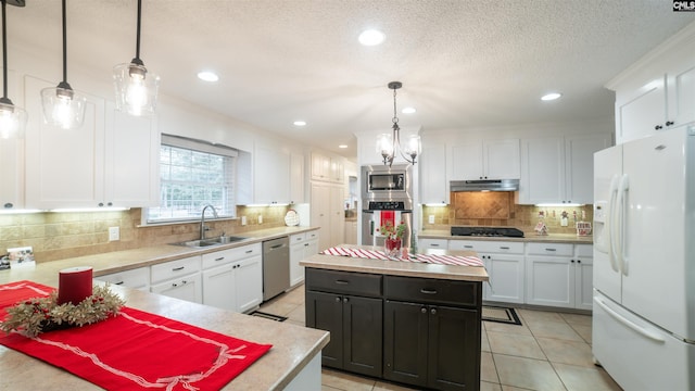 kitchen with hanging light fixtures, white cabinets, stainless steel appliances, and a kitchen island