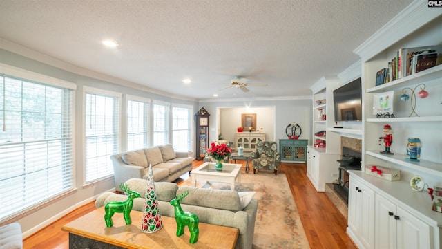 living room featuring ceiling fan, ornamental molding, a textured ceiling, and light hardwood / wood-style flooring