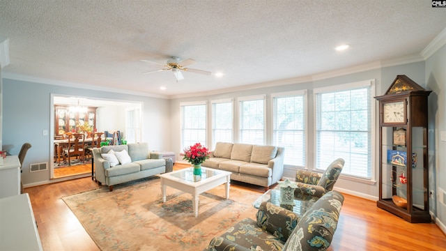 living room featuring ceiling fan, light hardwood / wood-style floors, a textured ceiling, and ornamental molding