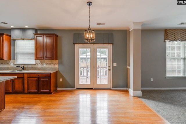 kitchen featuring backsplash, sink, decorative light fixtures, light hardwood / wood-style flooring, and an inviting chandelier