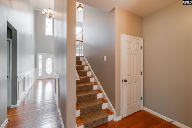 stairs featuring wood-type flooring and a notable chandelier