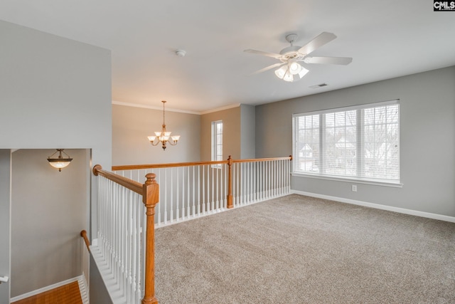 empty room featuring carpet, ceiling fan with notable chandelier, and crown molding