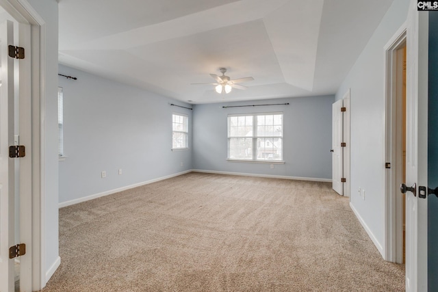 carpeted spare room with a tray ceiling and ceiling fan