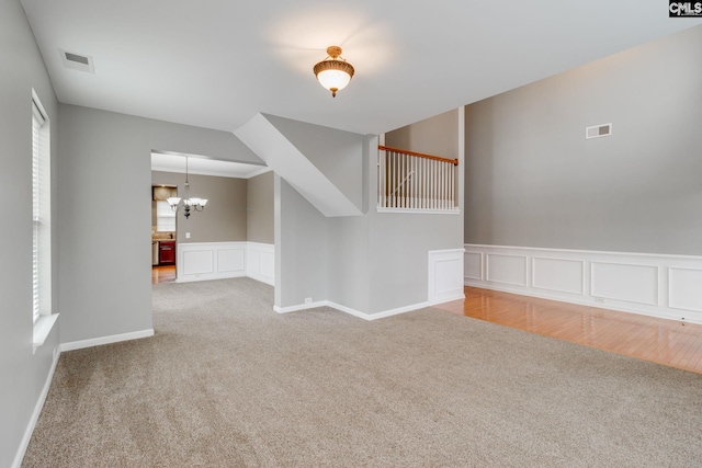 carpeted spare room with plenty of natural light and a notable chandelier