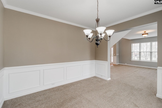 spare room with light colored carpet, crown molding, and an inviting chandelier