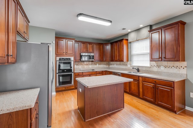 kitchen featuring a kitchen island, sink, light wood-type flooring, and stainless steel appliances