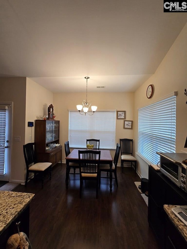 dining space featuring dark hardwood / wood-style flooring and a chandelier