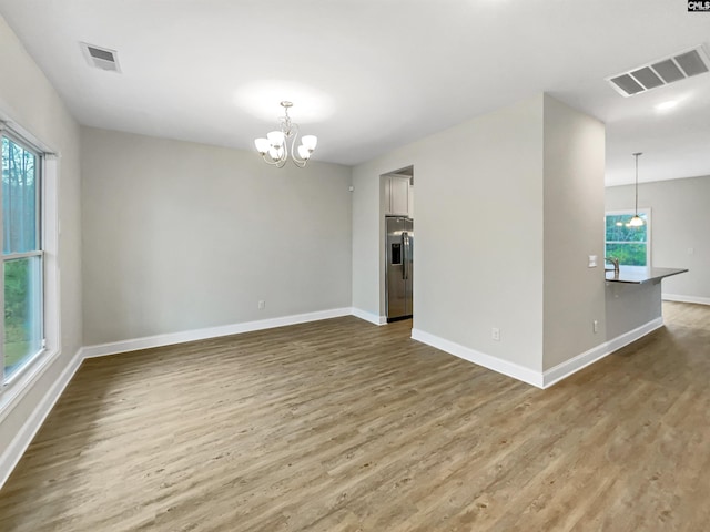 unfurnished room with hardwood / wood-style floors and a notable chandelier