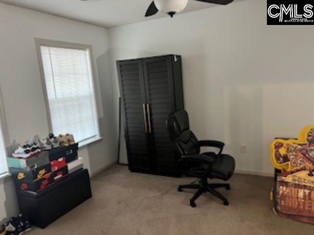 carpeted home office with a wealth of natural light and ceiling fan