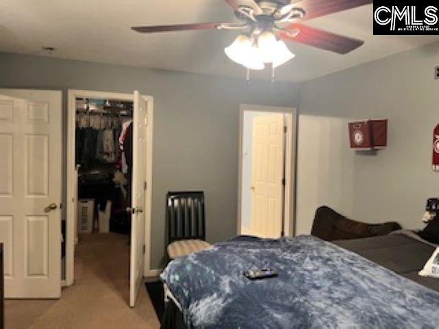 carpeted bedroom with a walk in closet, a closet, and ceiling fan