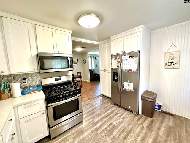 kitchen with decorative backsplash, light hardwood / wood-style flooring, white cabinets, and appliances with stainless steel finishes