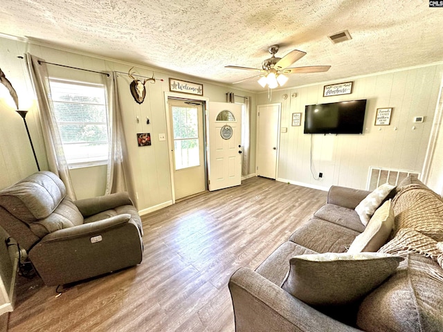 living room featuring ceiling fan, crown molding, wood-type flooring, and a textured ceiling