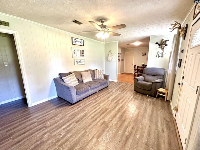 living room featuring wood-type flooring, a textured ceiling, ceiling fan, and wood walls