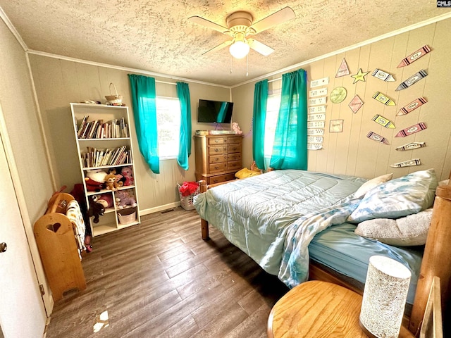 bedroom featuring a textured ceiling, ceiling fan, wooden walls, crown molding, and hardwood / wood-style flooring