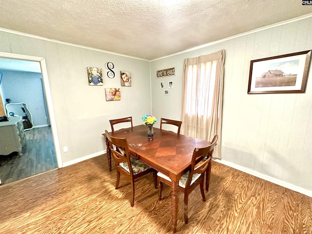 dining area featuring ornamental molding, a textured ceiling, and light wood-type flooring