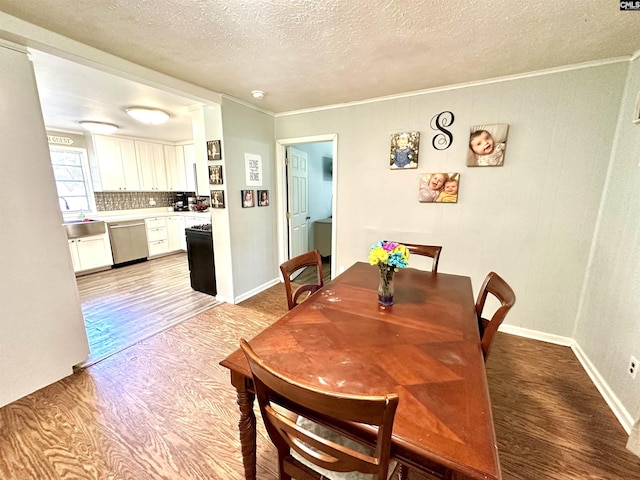 dining area featuring a textured ceiling, light wood-type flooring, and crown molding