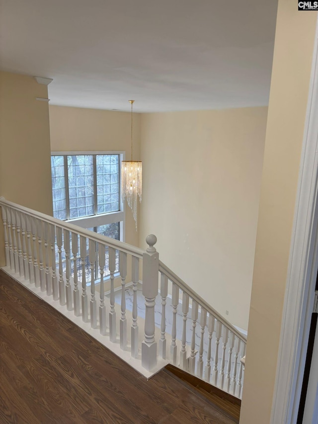 staircase featuring wood-type flooring and a notable chandelier