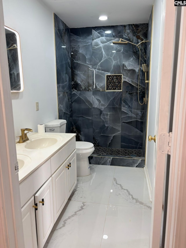 bathroom featuring a tile shower, vanity, and toilet