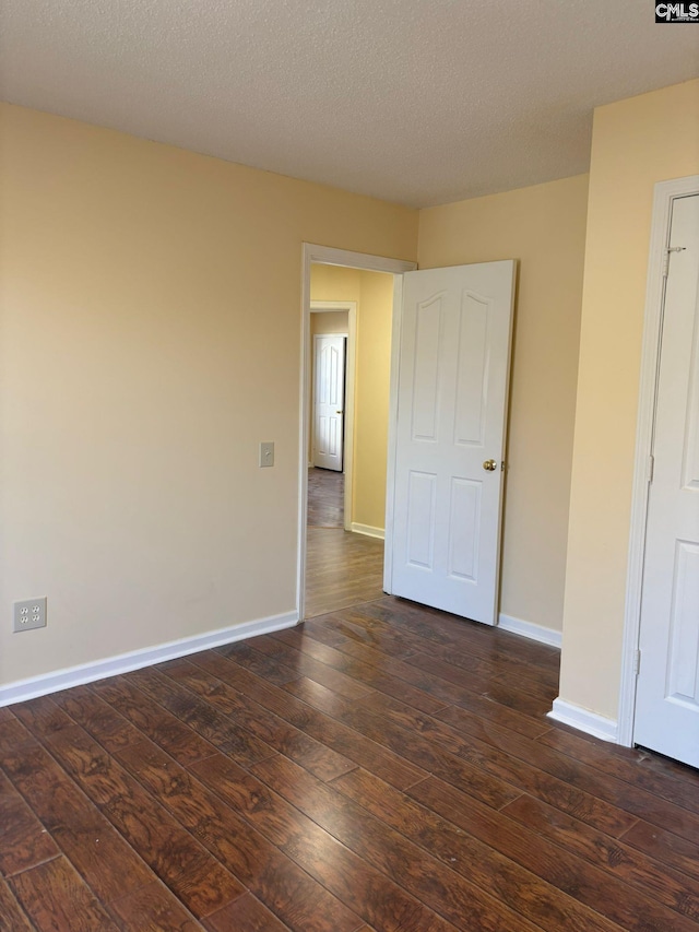 unfurnished room featuring a textured ceiling and dark wood-type flooring