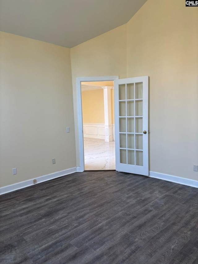 spare room with dark wood-type flooring and lofted ceiling