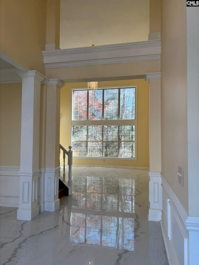 unfurnished room featuring decorative columns, crown molding, and a high ceiling