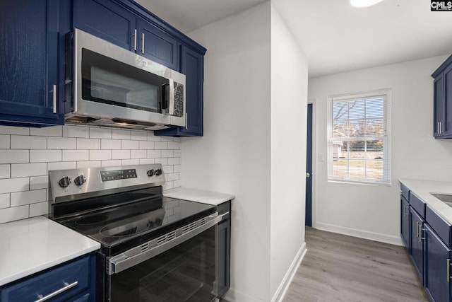 kitchen with decorative backsplash, blue cabinetry, appliances with stainless steel finishes, and light hardwood / wood-style flooring