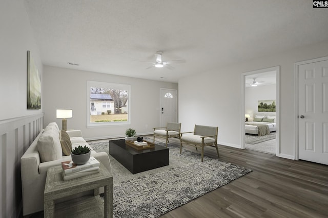 living room with dark hardwood / wood-style floors, ceiling fan, and a textured ceiling