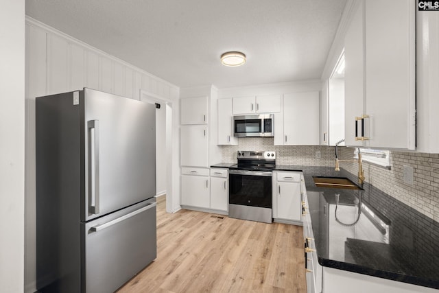 kitchen featuring white cabinets, sink, decorative backsplash, appliances with stainless steel finishes, and light hardwood / wood-style floors