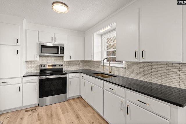 kitchen featuring ornamental molding, stainless steel appliances, sink, light hardwood / wood-style floors, and white cabinetry