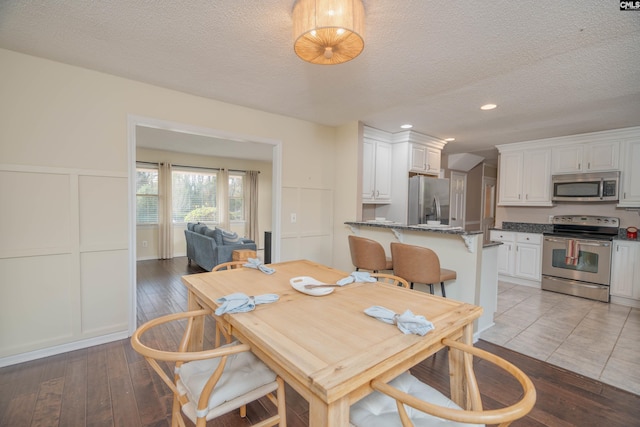 dining area featuring a textured ceiling and light hardwood / wood-style flooring