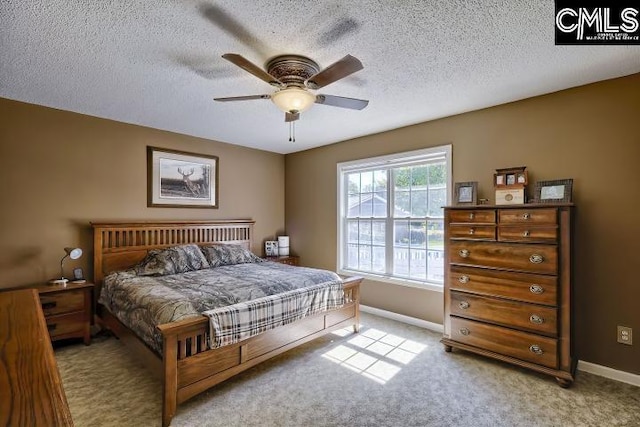 carpeted bedroom with ceiling fan and a textured ceiling