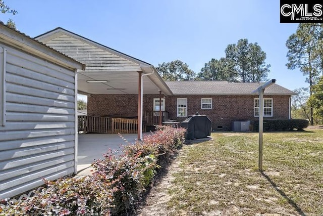 back of property with central AC unit and a lawn