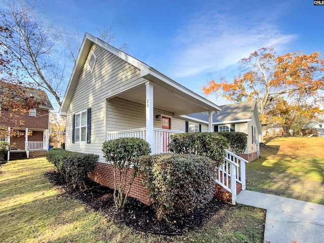 view of side of home featuring a lawn and covered porch