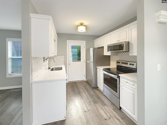 kitchen with white cabinetry, sink, stainless steel appliances, and light hardwood / wood-style floors