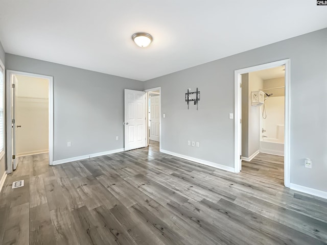 unfurnished bedroom with hardwood / wood-style flooring, ensuite bath, a spacious closet, and a closet