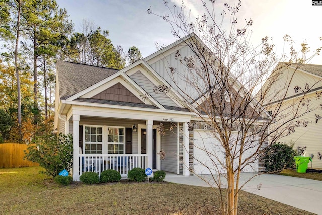 view of front of property featuring a front lawn, covered porch, and a garage